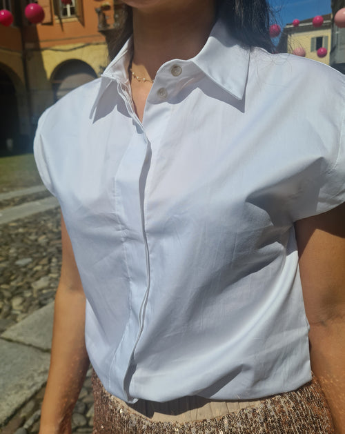 Camicia smanicata a spalla ampia in tela vela di cotone, sfiancata, bottoni a scomparsa, collo a camicia, fondo stondato.  Disponibile in bianco e nero.  Nuova collezione estate Kartika.